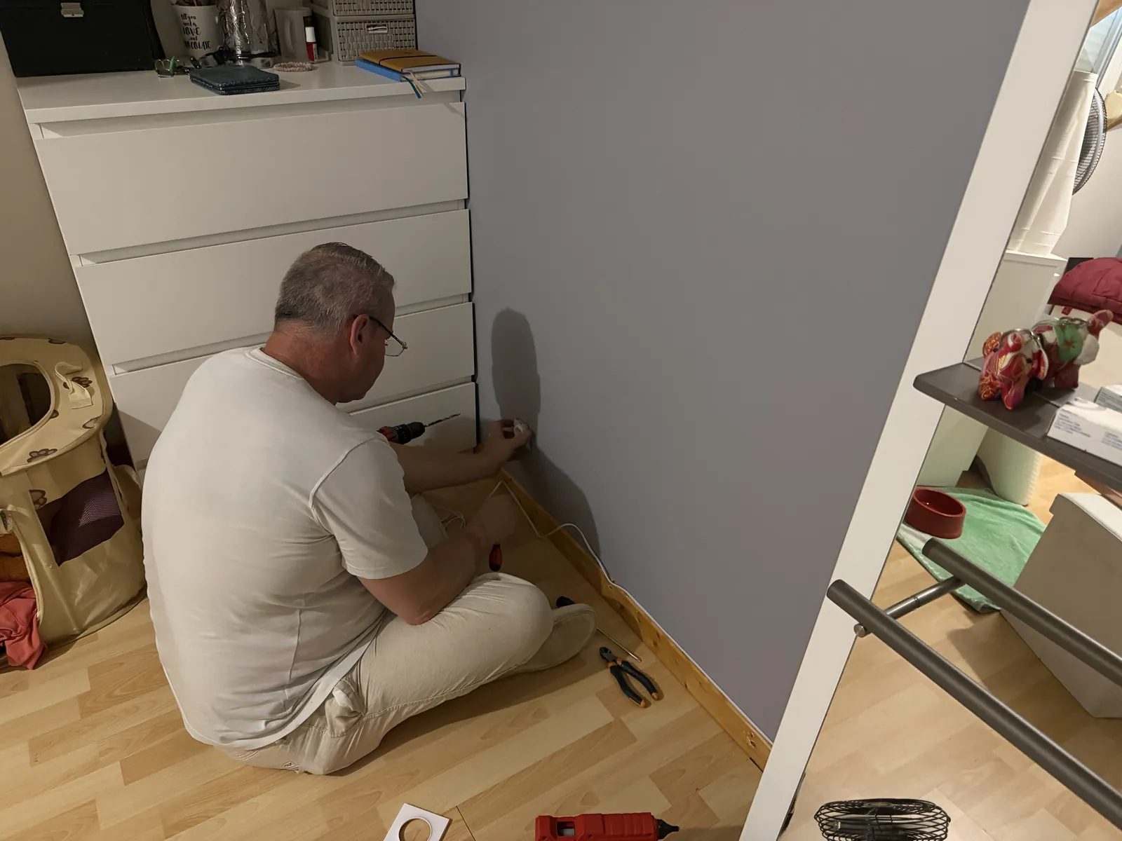 Raccordement d'un monte-escalier électrique : l'installateur pose une prise au pied du mur